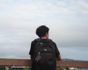 A person with a backpack looks out at the sky.